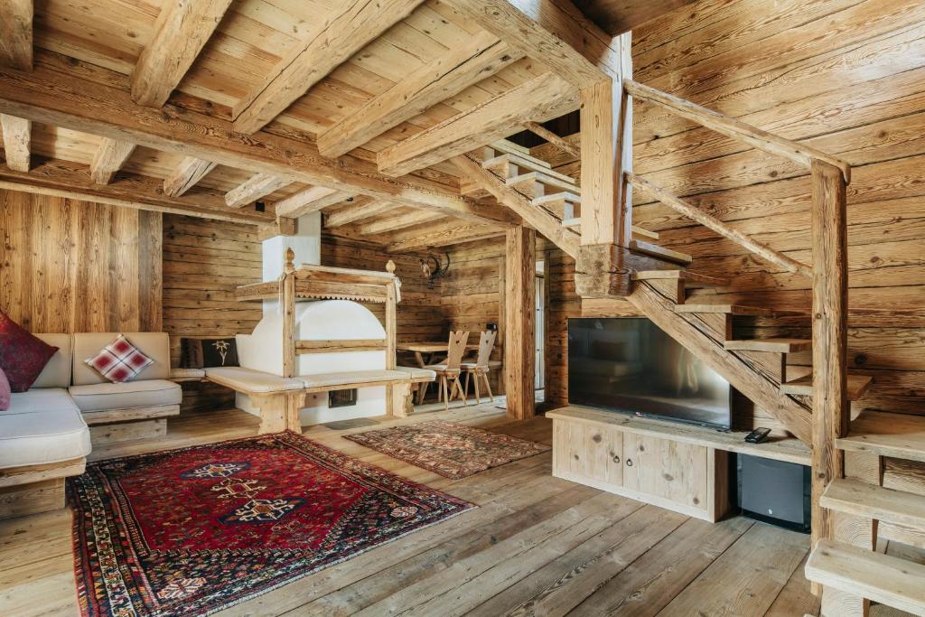 Casa Aurea, Cortina d'Ampezzo — living room with majolica stove and timber staircase